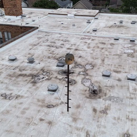 Drone inspection image of a flat commercial roof with mounting equipment and wear patterns.