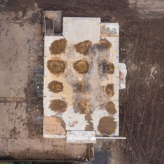 Aerial drone view of water damage patterns on a flat commercial roof surface.