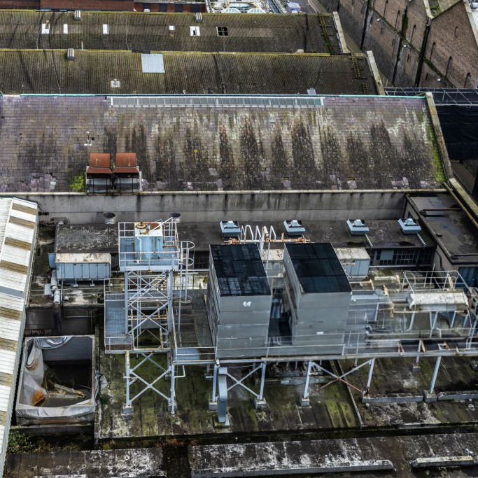 Drone photograph of industrial rooftop with HVAC equipment and weathered surfaces.