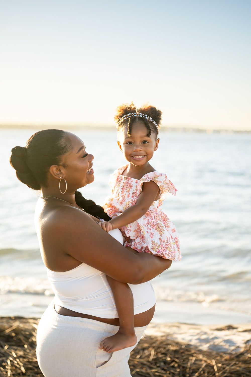 A joyful moment captured at sunset on the beach as a parent and child share laughter and embraces together.