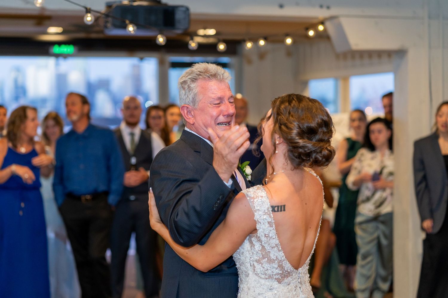 A tender moment on the dance floor at a wedding reception with guests watching in the background.