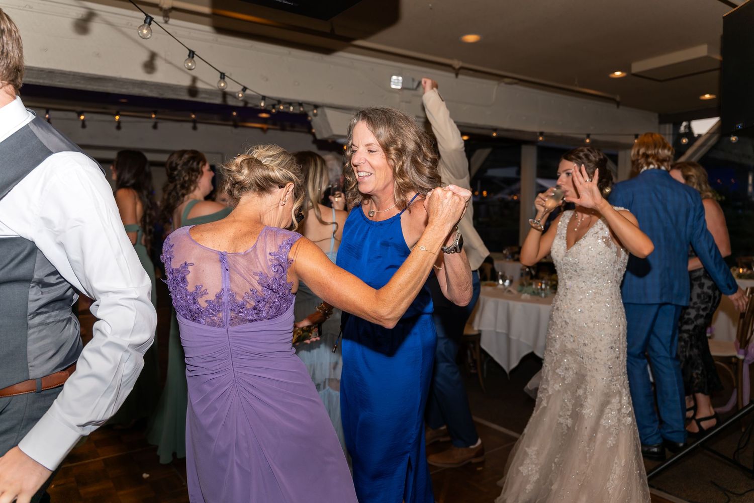 Guests dancing and celebrating at a wedding reception with people in purple and blue formal attire.