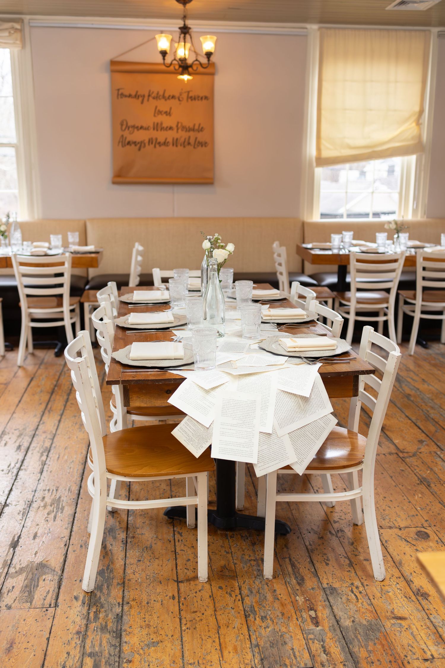 Reception room setup with white chairs and rustic wooden tables arranged for a special event.