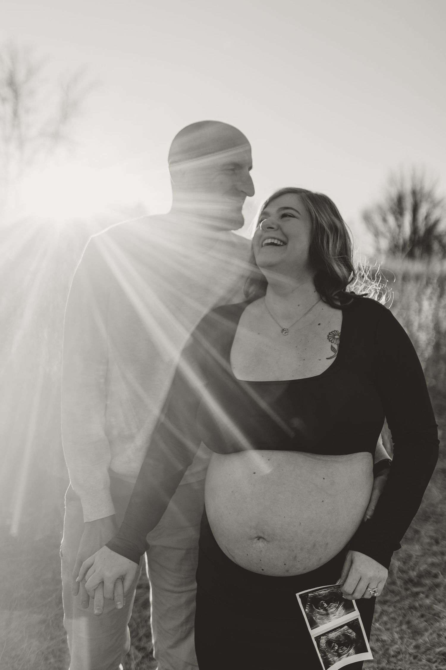 Golden Hour Maternity Session held in Spartanburg South Carolina. Pregnant woman is smiling while the flare of the sun is shining.