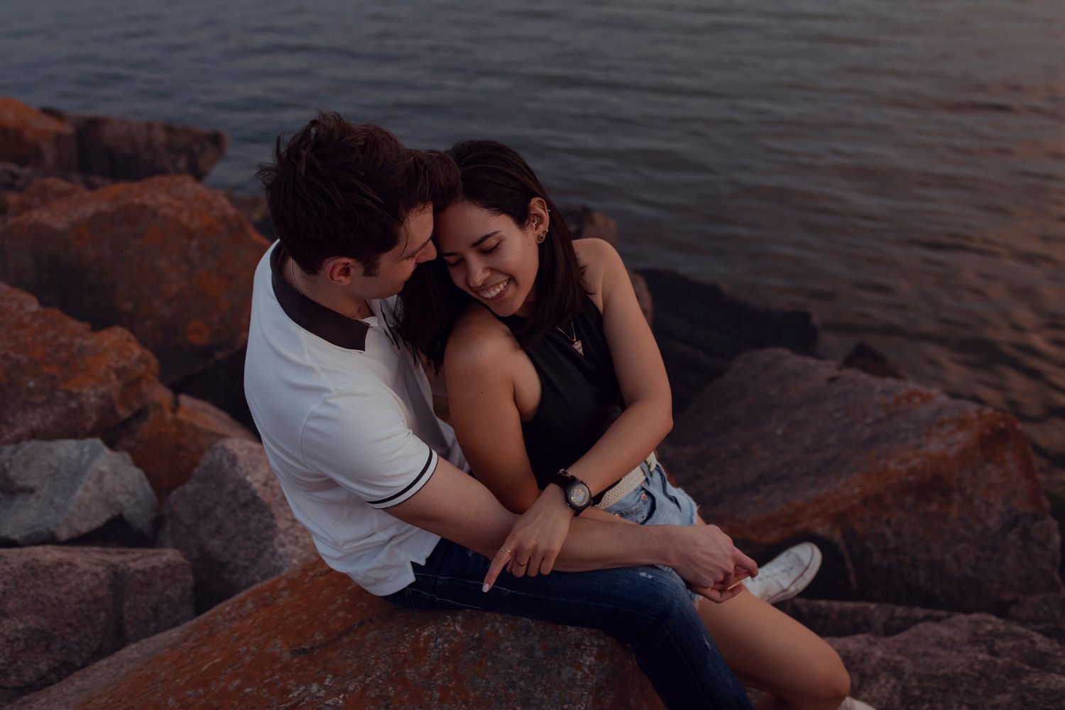 Couple sits on armour rock, enjoying the sunset in downtown Kingston, Ontario, CA.
