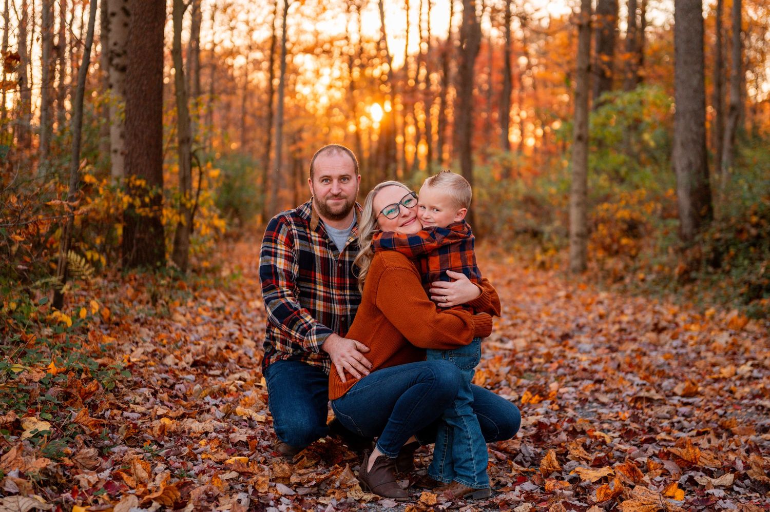 Autumn sunset in the woods with orange foliage covering the ground and golden light filtering through the trees.