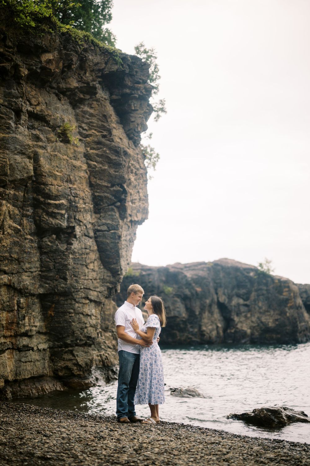 A romantic moment shared along a rocky coastline with dramatic cliffs and crashing waves.