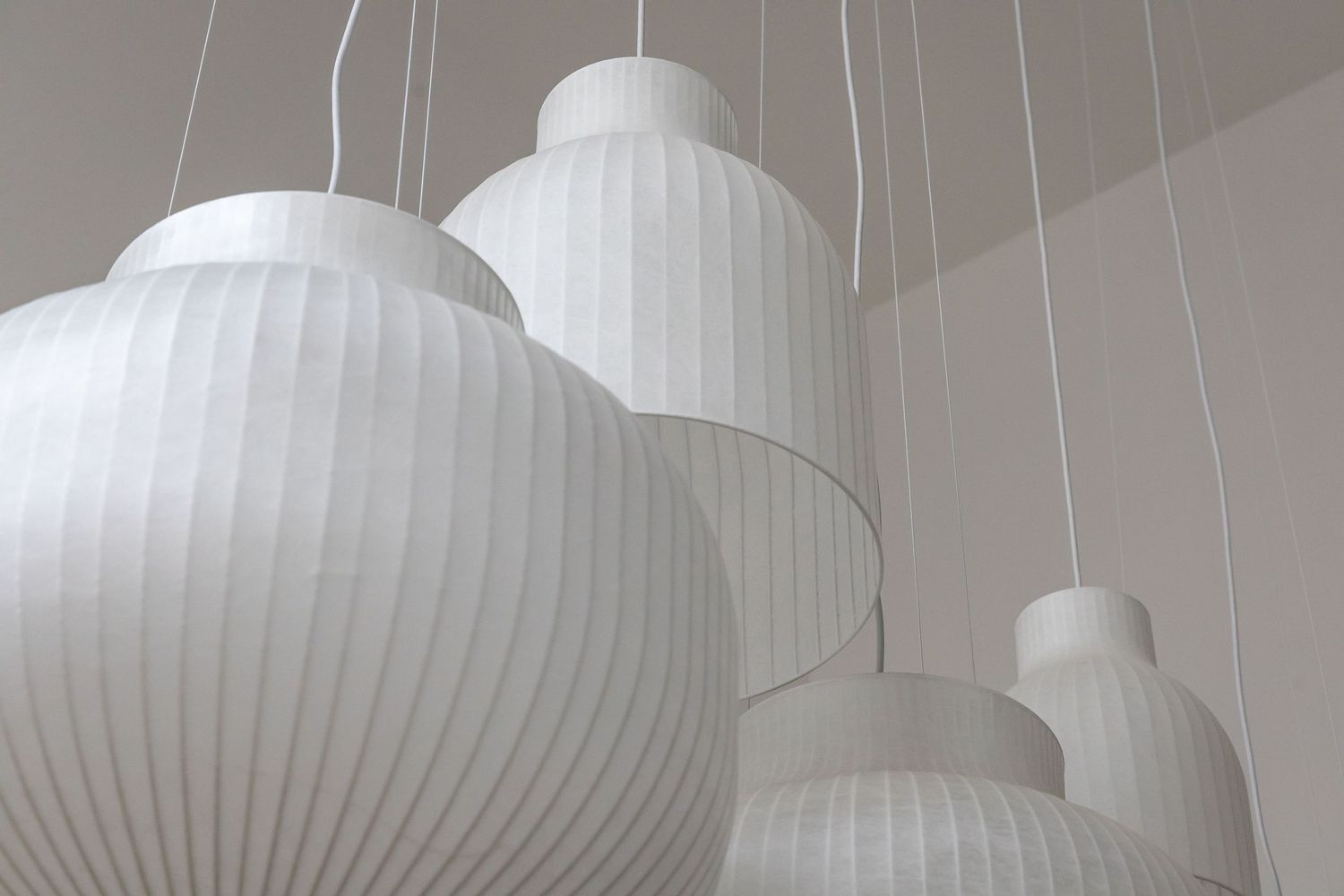 Modern white ribbed pendant lantern lights hanging from the ceiling create a minimalist architectural element.