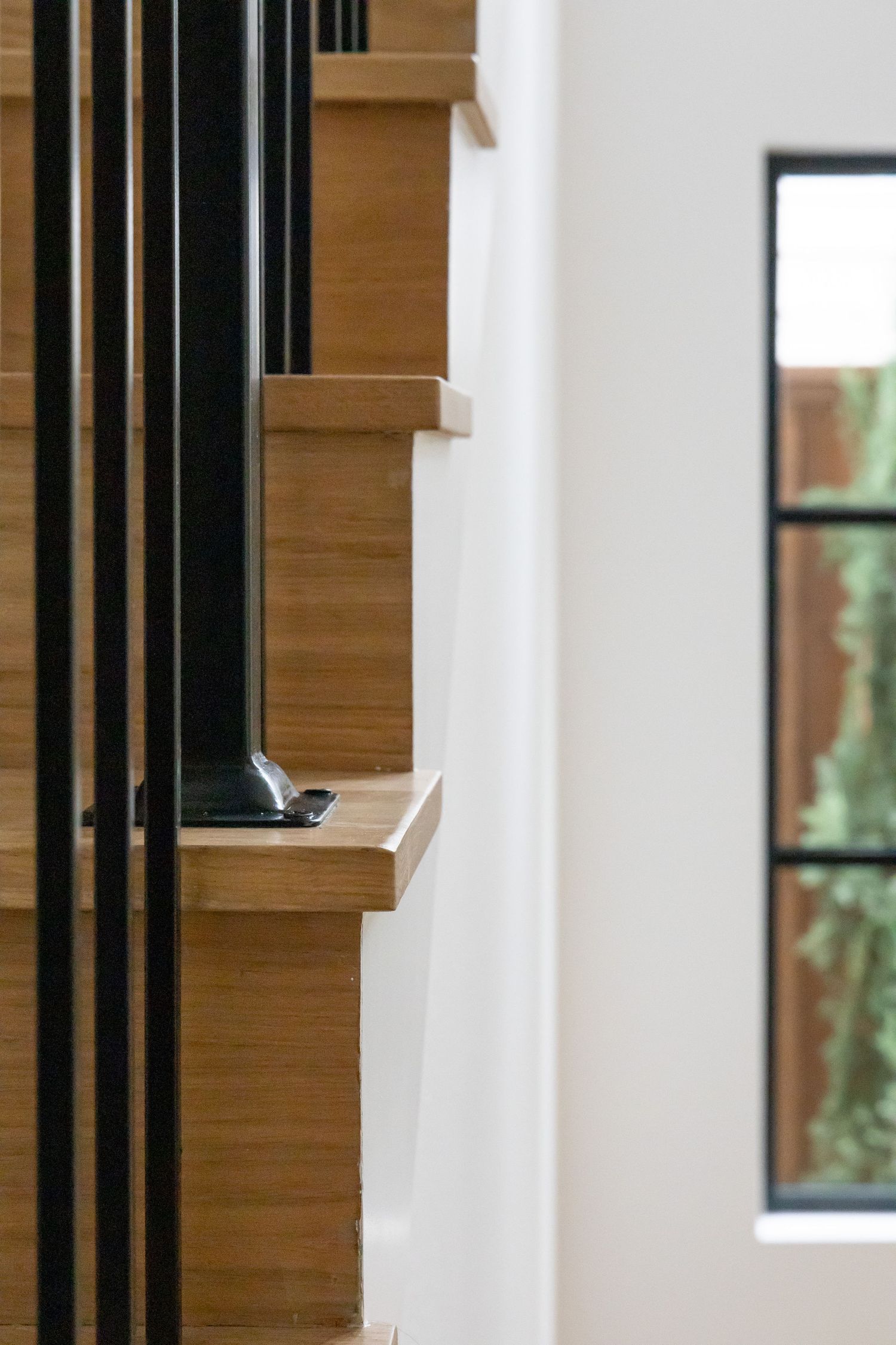 Close-up detail of wooden stairs with black metal railings in a contemporary home interior.
