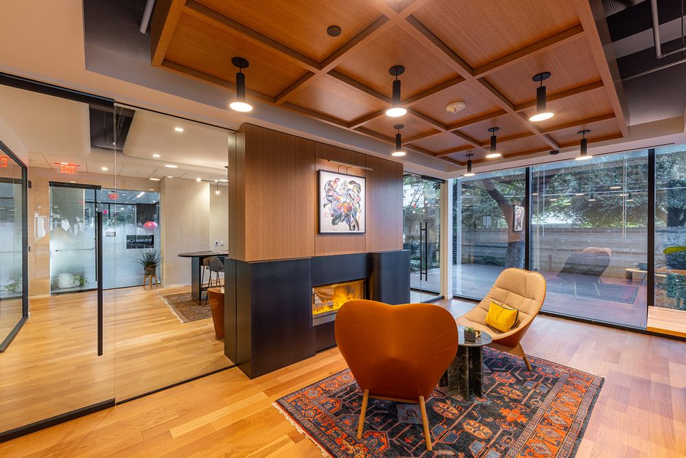 Modern office interior with wooden ceiling panels, glass walls, and contemporary furniture creates a warm professional atmosphere.