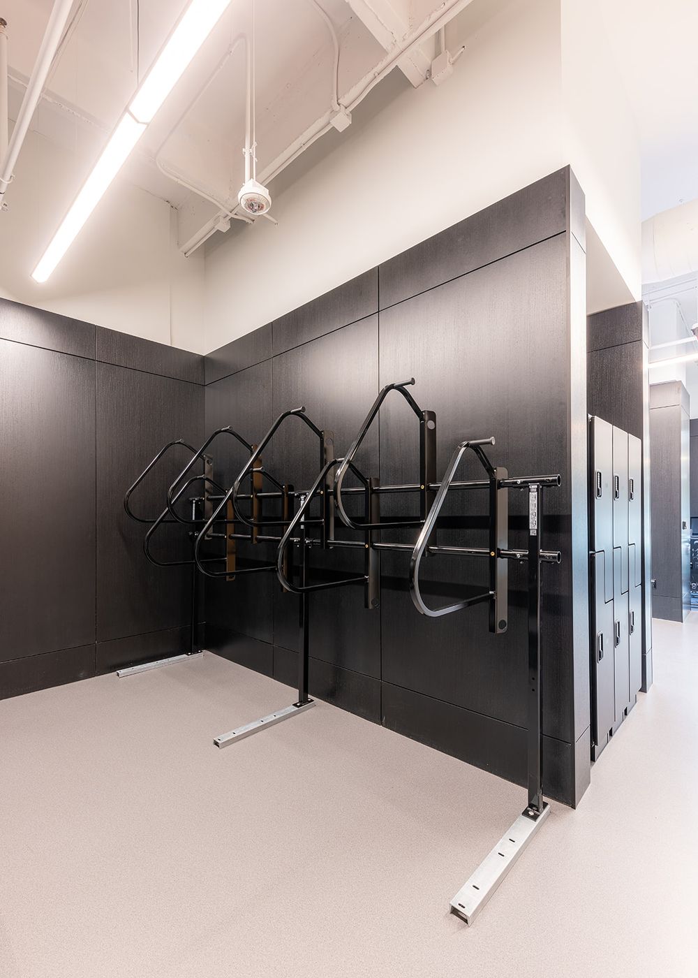 Long narrow interior hallway with black accent wall features multiple mounted bike racks in minimalist modern design.