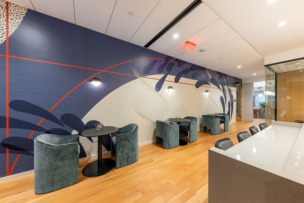Modern conference room with curved wall mural featuring blue and orange design elements and green velvet seating.