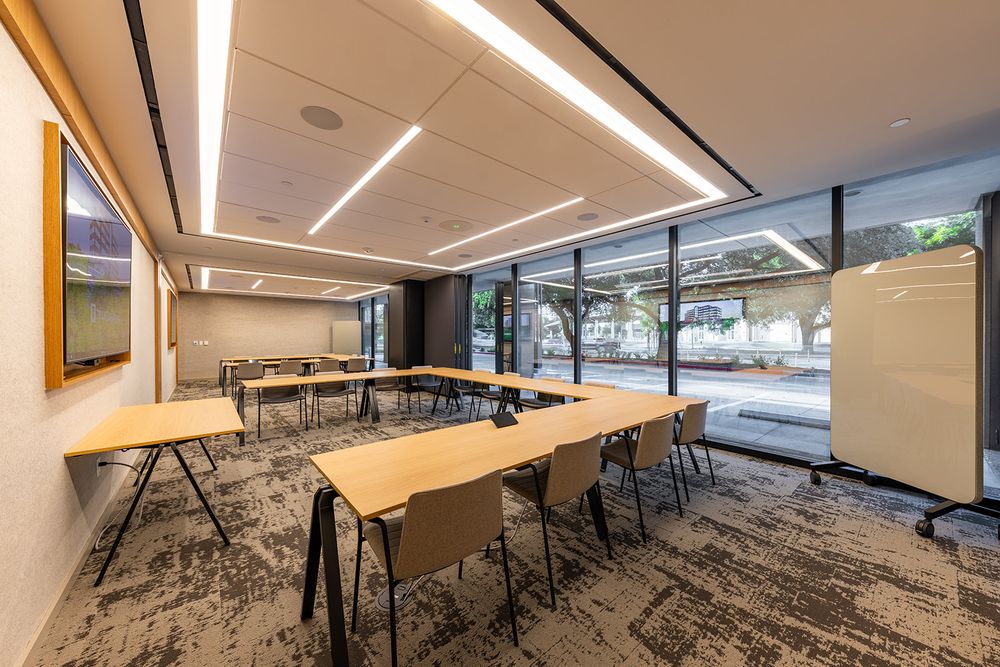 Modern office meeting room with glass walls, recessed lighting, and geometric patterned carpeting.