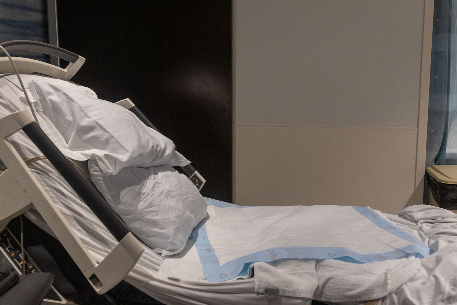 Medical monitoring equipment and hospital bed shown in dark lighting.
