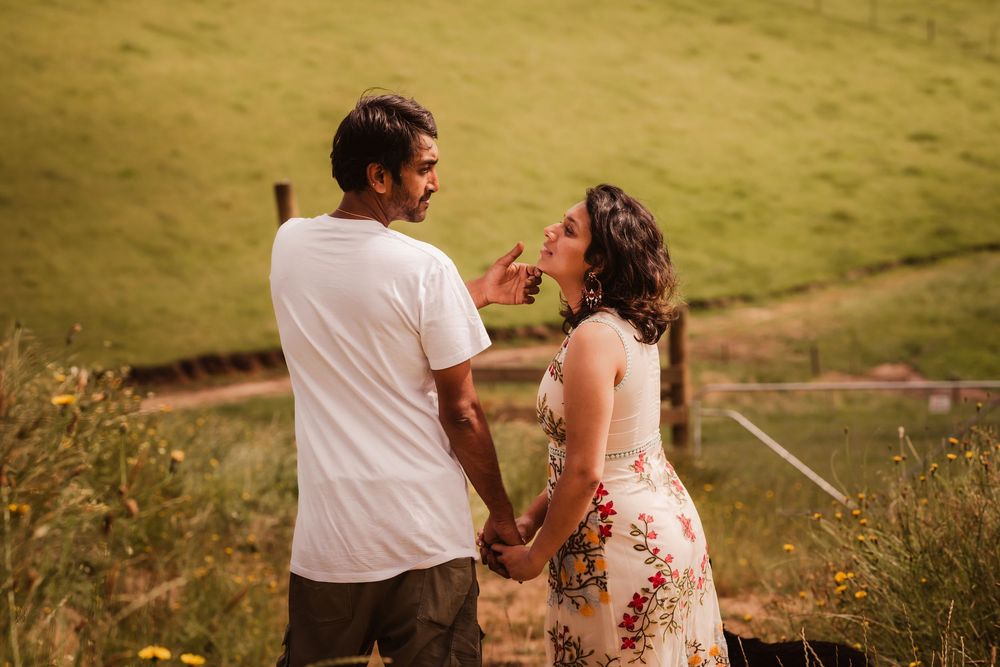 A couple embraces in a golden grassy field at sunset creating a romantic silhouette against the warm light.