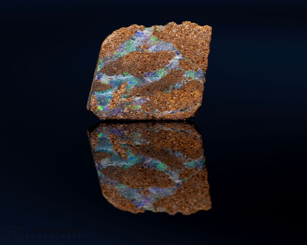 Close up (macro) of small piece of opal with black background.
