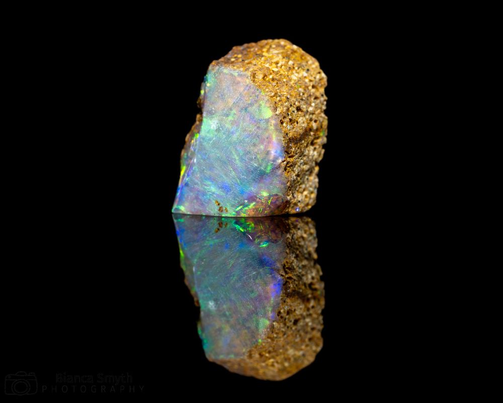 Close up (macro) of small piece of opal with black background.