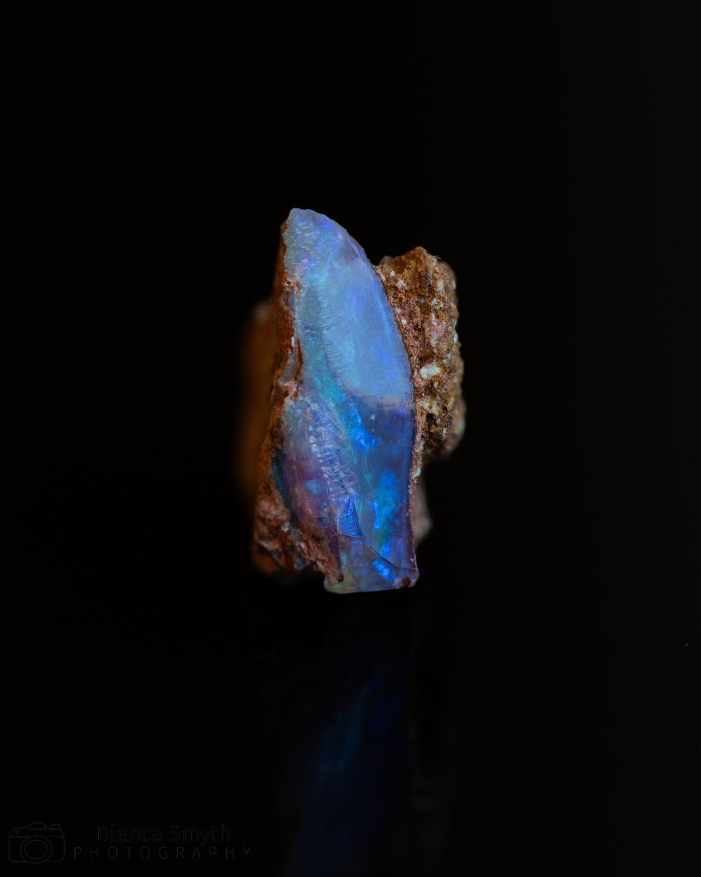 Close up (macro) of small piece of opal with black background.