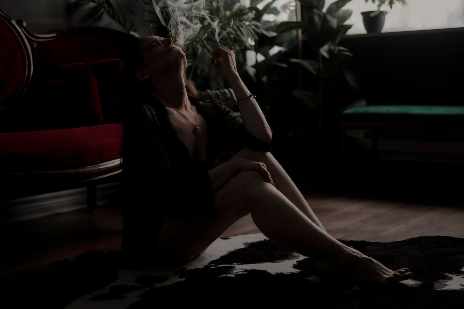 Silhouette reflection in mirror with houseplants creating moody atmospheric composition in dim lighting.
