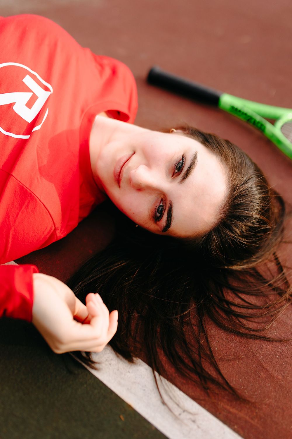 Fashion portrait on tennis court with person in bright red athletic wear.