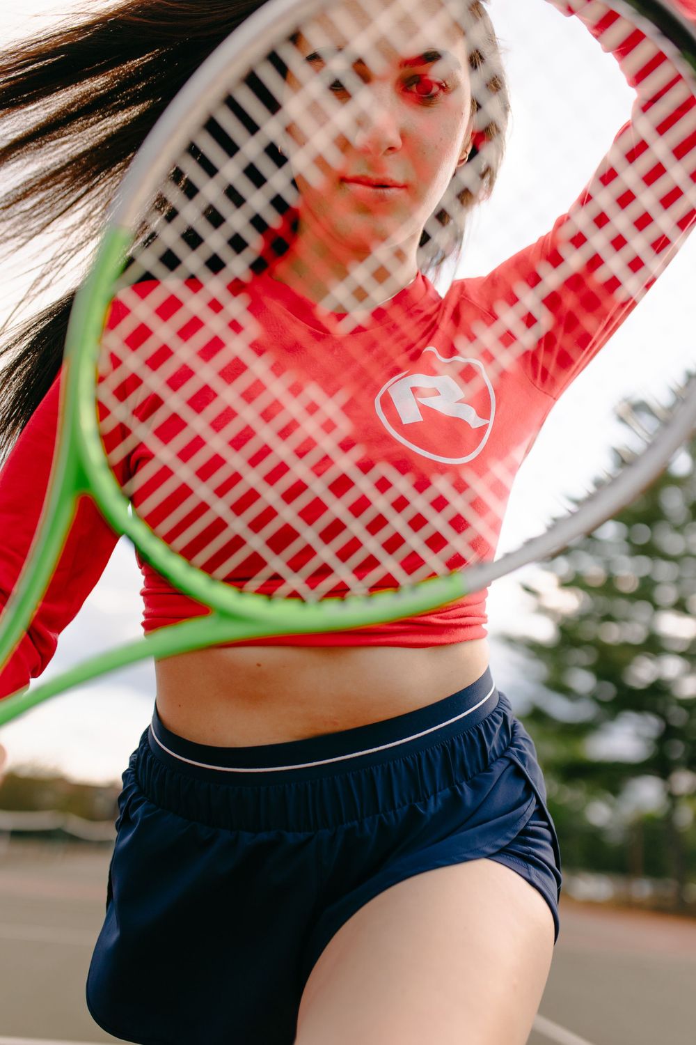 Sports lifestyle photo with tennis racket and navy athletic wear against gingham pattern.