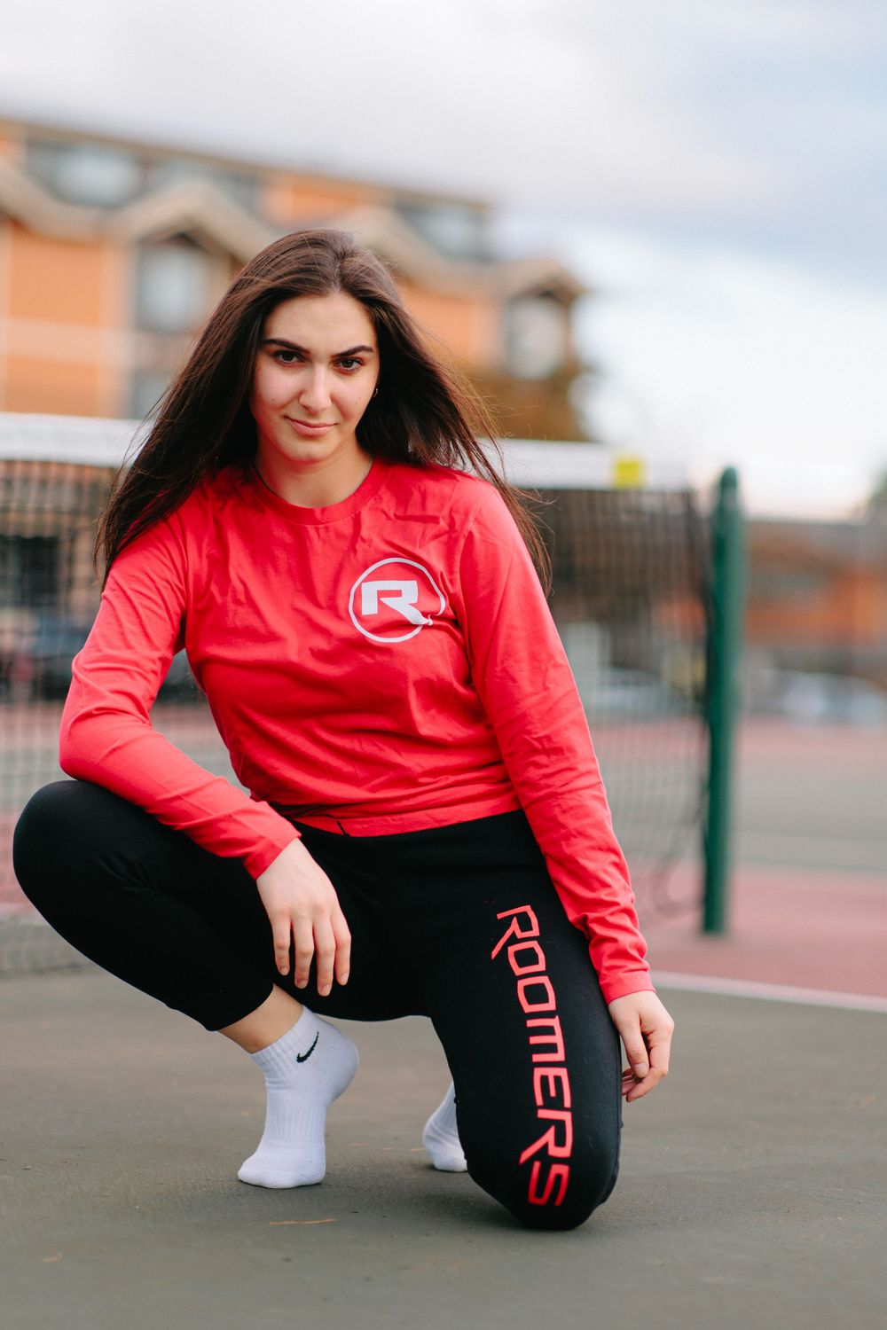 Person in red Roomers athletic wear crouches on court wearing black leggings and white socks.