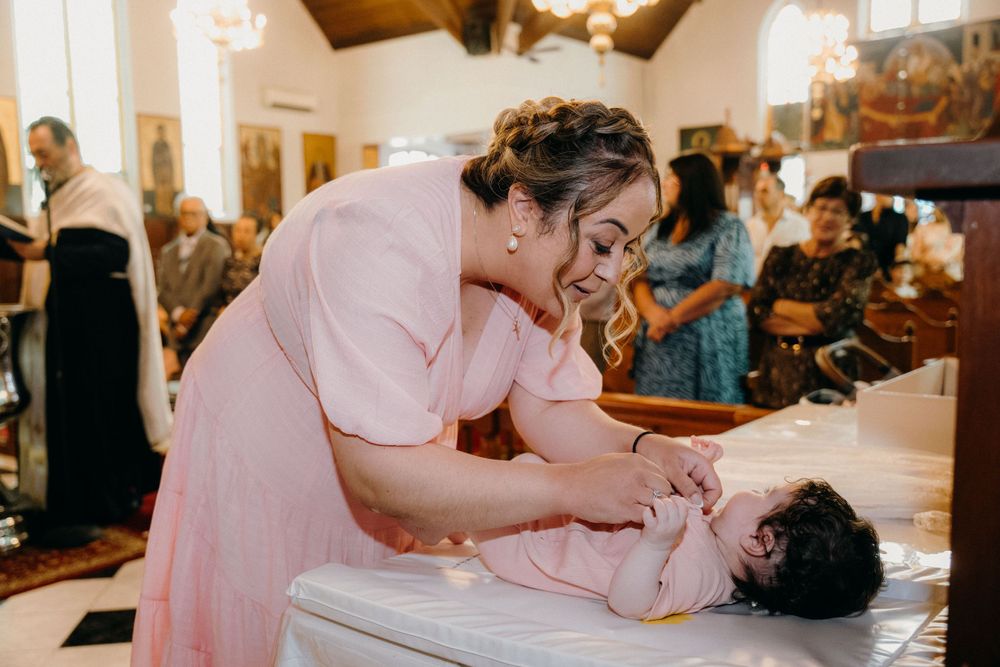 Parents wrap baby in soft white towel after baptism in Melbourne intimate family moment captured by a quality photographer based in mel.