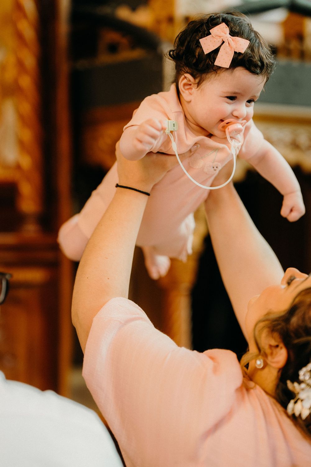 Proud mother hold her baby after a beautiful Melbourne christening, perfectly captured in  candid style by baptism photographer in Melbourne