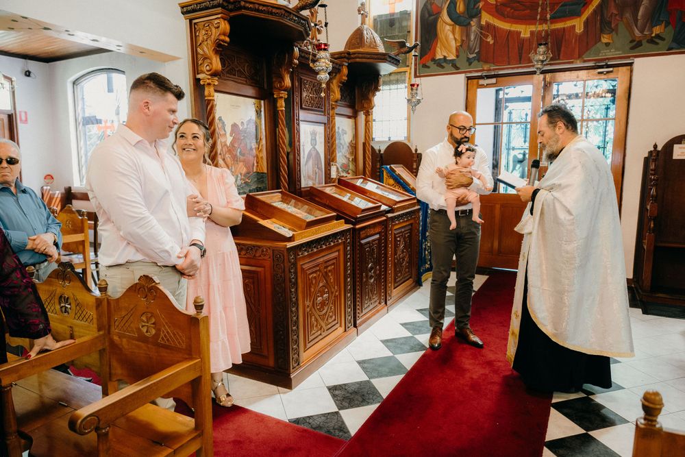 Melbourne baptism photographer captures parents' joyful expressions as they watch their baby during the sacred christening moment.