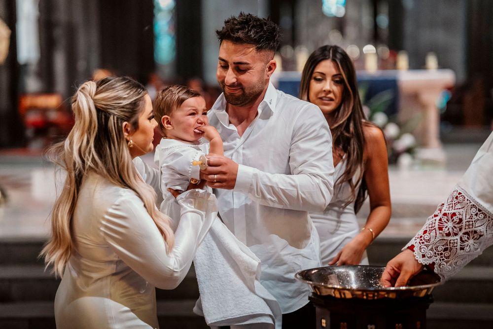 Melbourne baptism photographer captures parents’ overwhelmed smiles as they lovingly watch their baby post-ceremony in a peaceful moment.