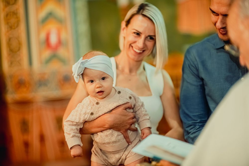 Baby held over baptismal font in Melbourne church, captured candidly with grace, emotional storytelling by a quality baptism photographer