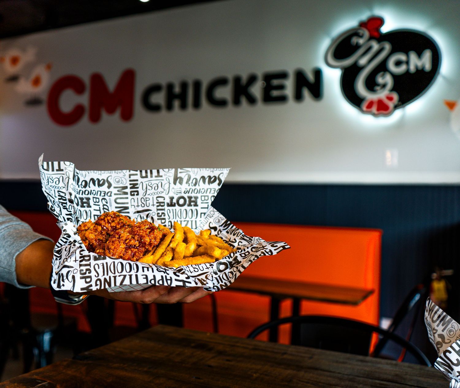 Orange and white restaurant signage with artistic chicken design elements.