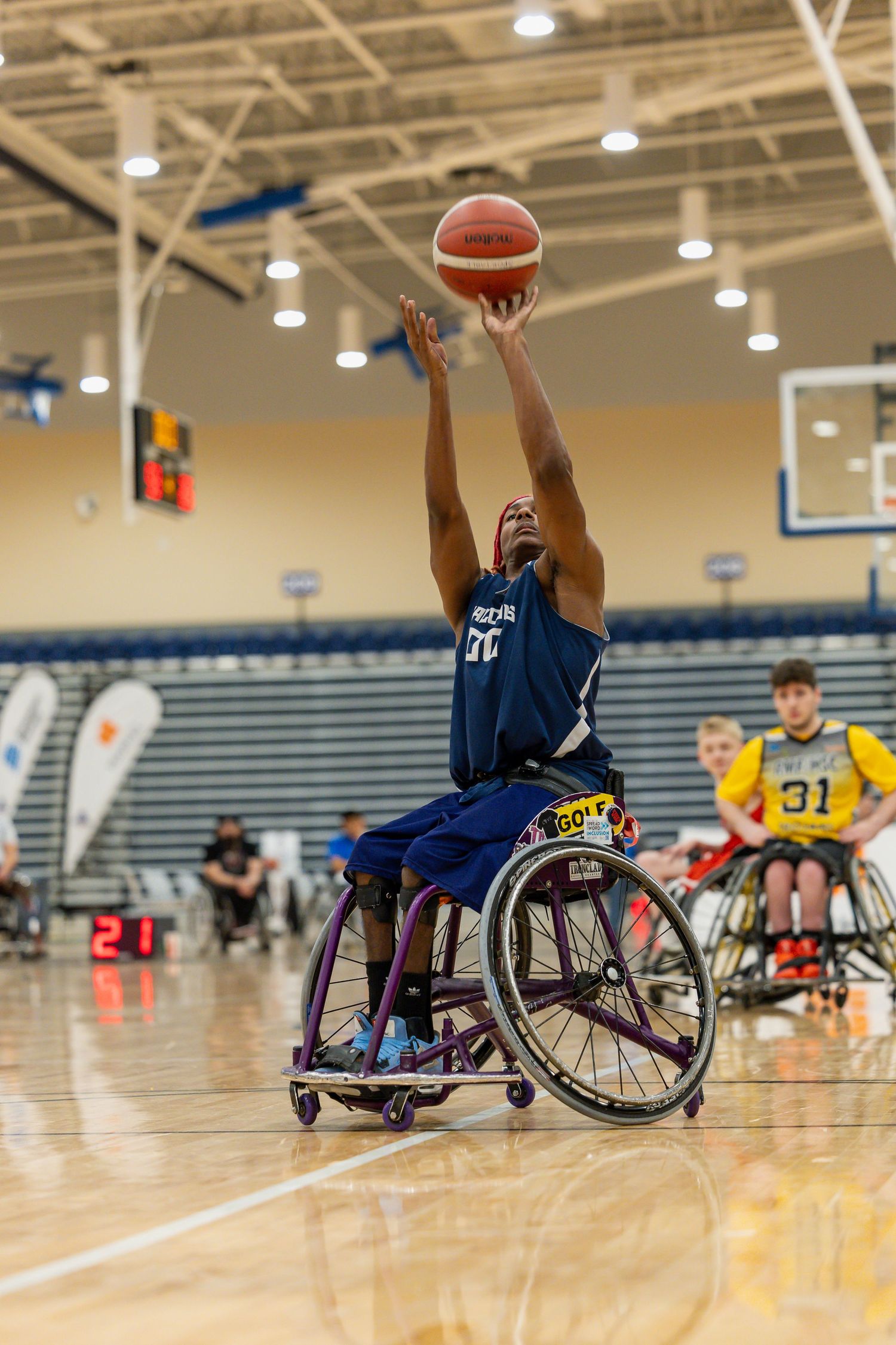 Wheelchair basketball players compete on an indoor court during an intense game.