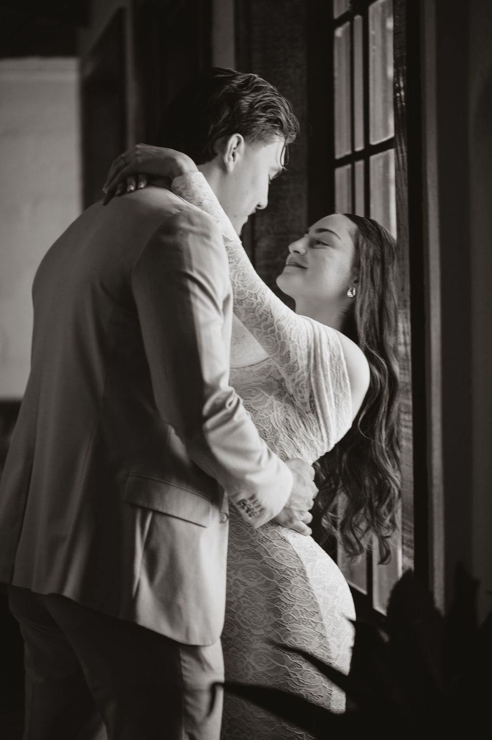 Black and white series of intimate romantic moments by a window showing a couple embracing in dramatic lighting.