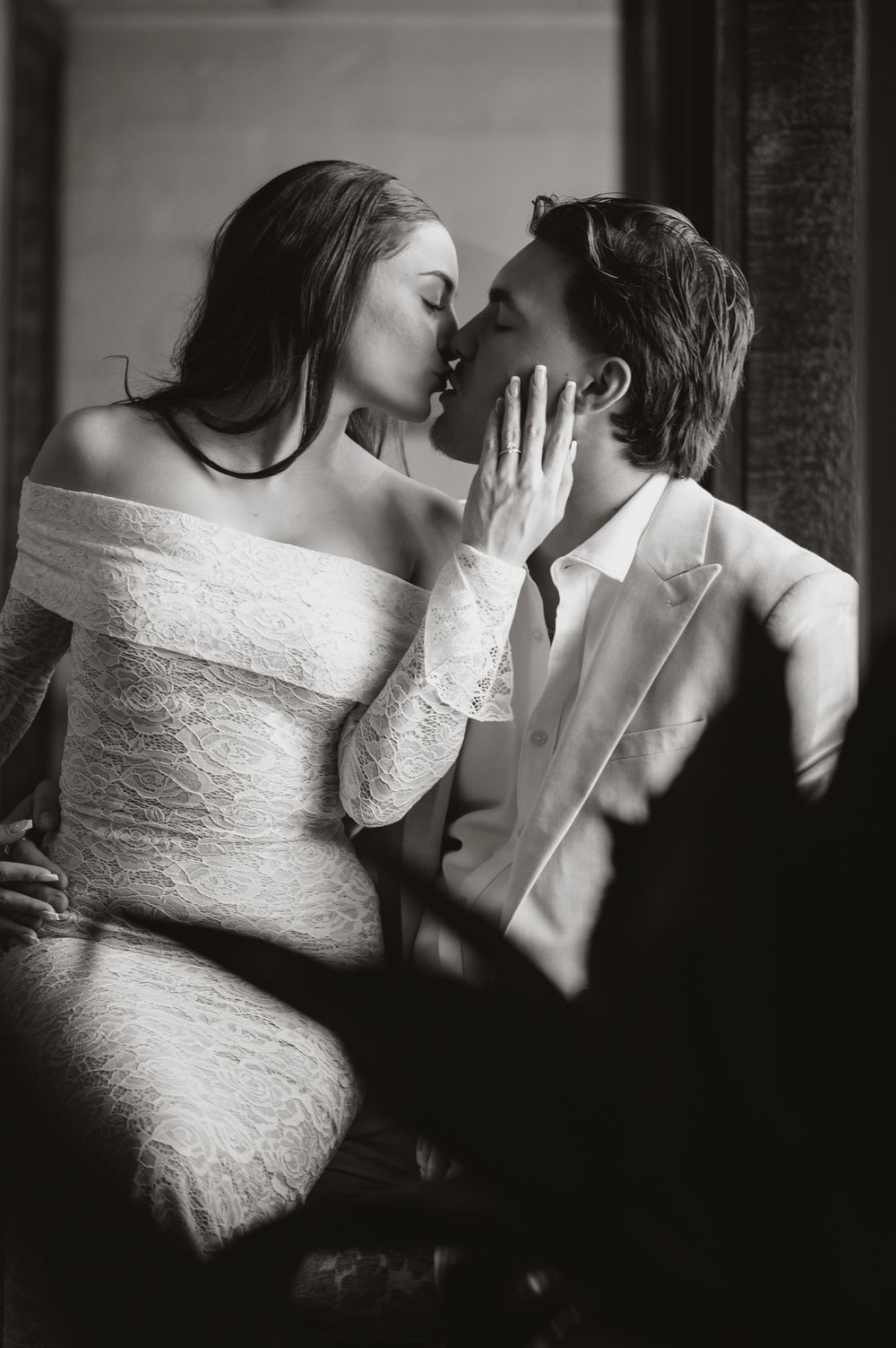 A romantic black and white photograph shows an intimate kiss between a couple, with the woman wearing a lace dress.