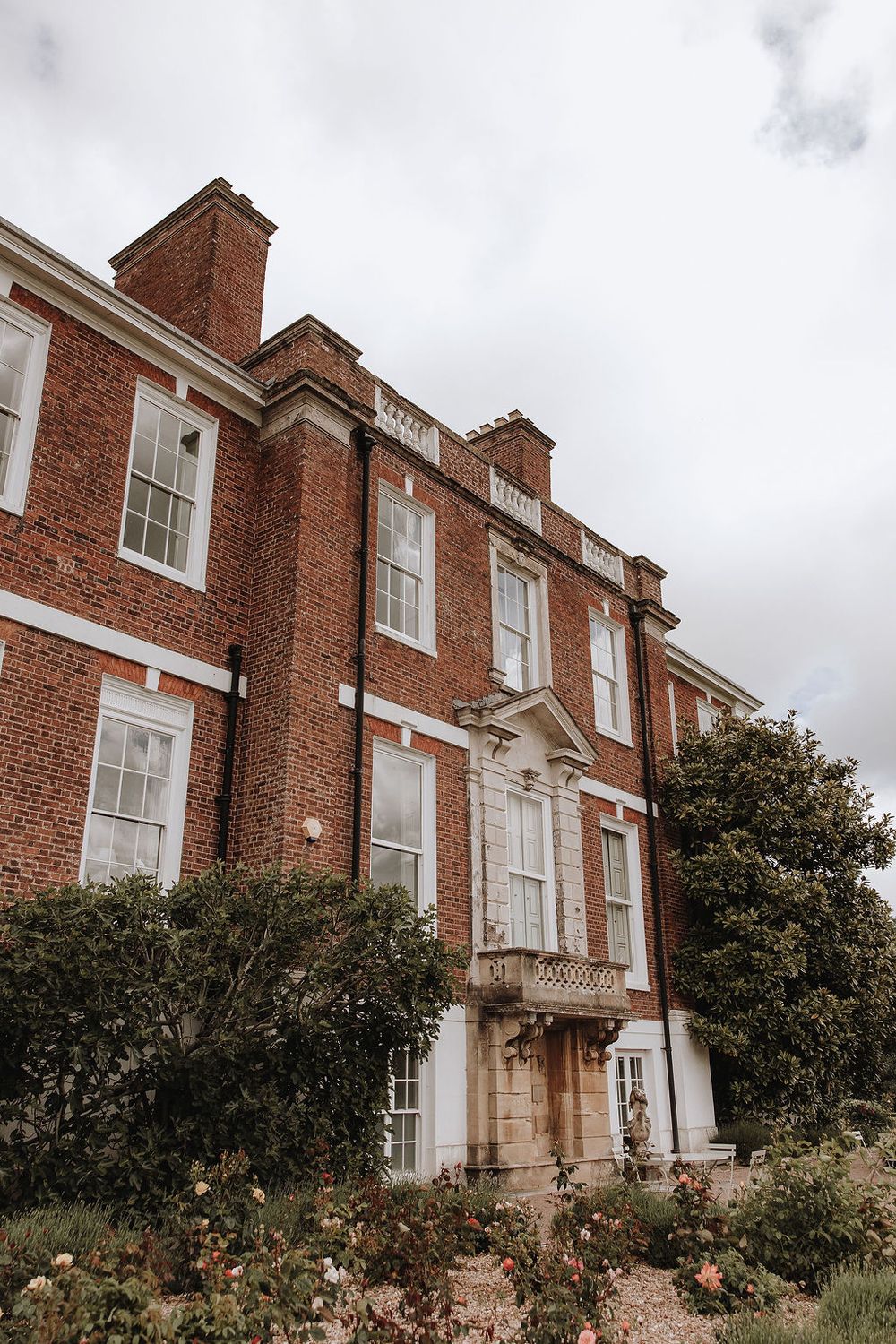 A brick Georgian-style house with white windows and a classic chimney viewed from different angles against a cloudy sky.