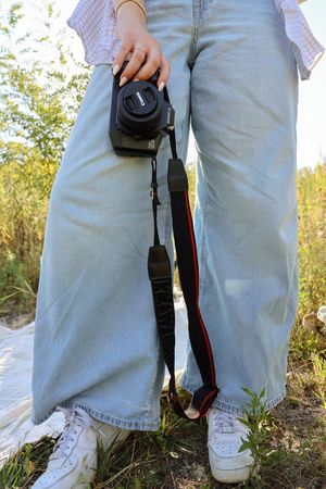 Close-up of casual attire and camera equipment on grassy ground in natural lighting.