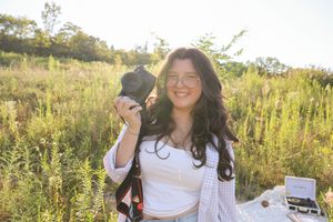 Casual outdoor photoshoot setup in a golden meadow with camera equipment.