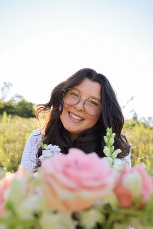 Pink roses and white flowers in foreground with sunlit meadow background.