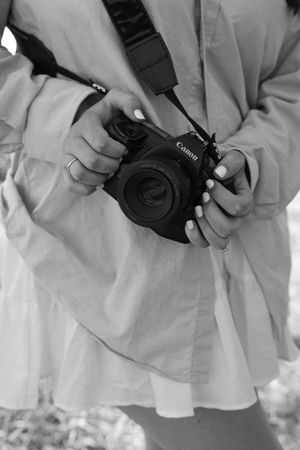 Close-up black and white shot of hands holding a Canon camera.
