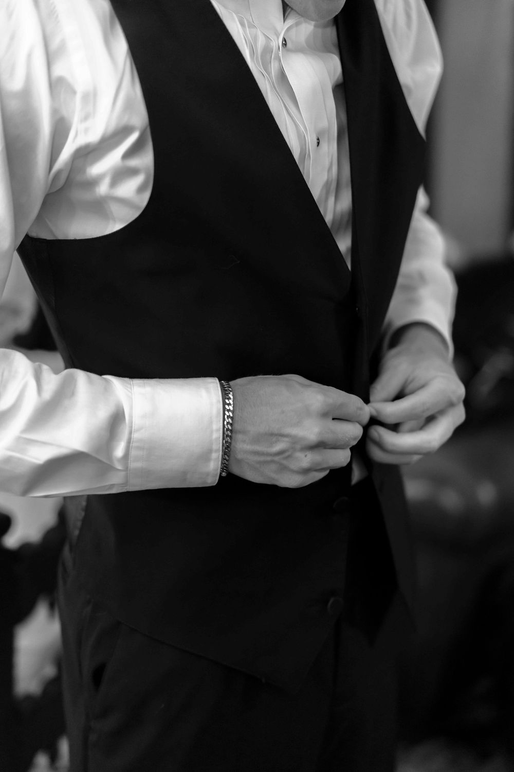 A black and white photo showing multiple people in formal attire wearing white dress shirts and black vests.