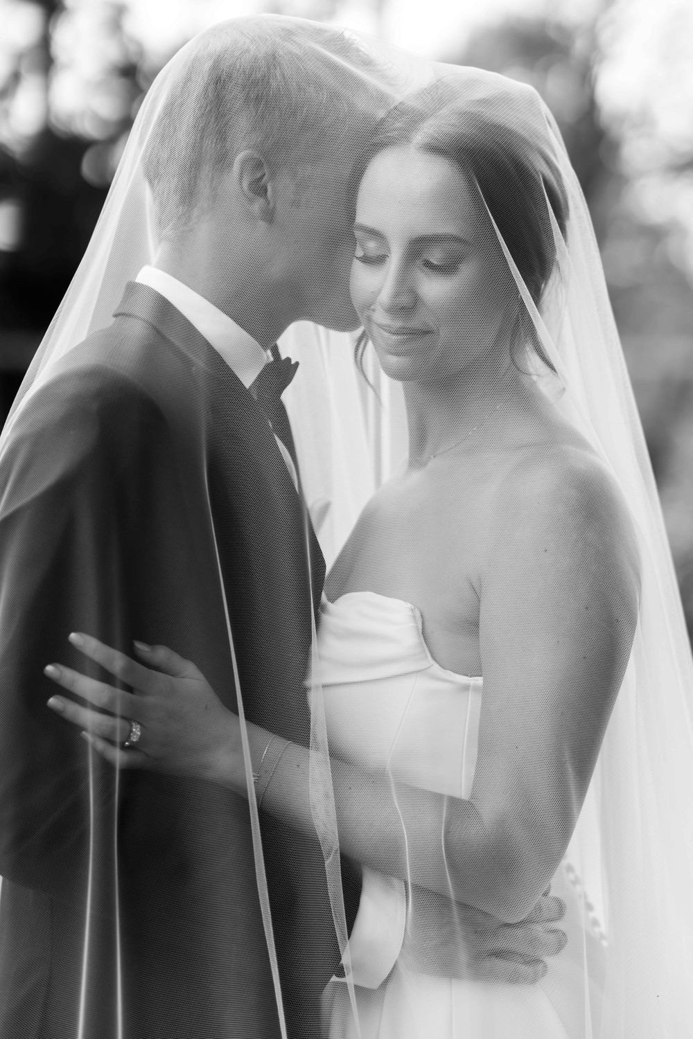A romantic black and white sequence of intimate wedding moments showing a couple embracing under a flowing veil.