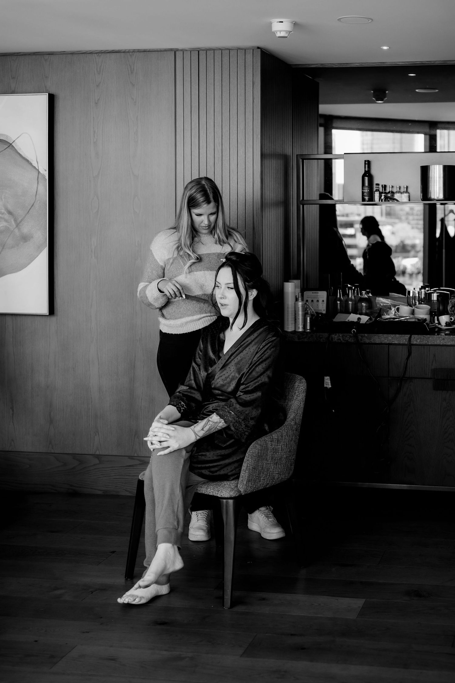 Black and white photo of salon services being provided in a modern interior setting.