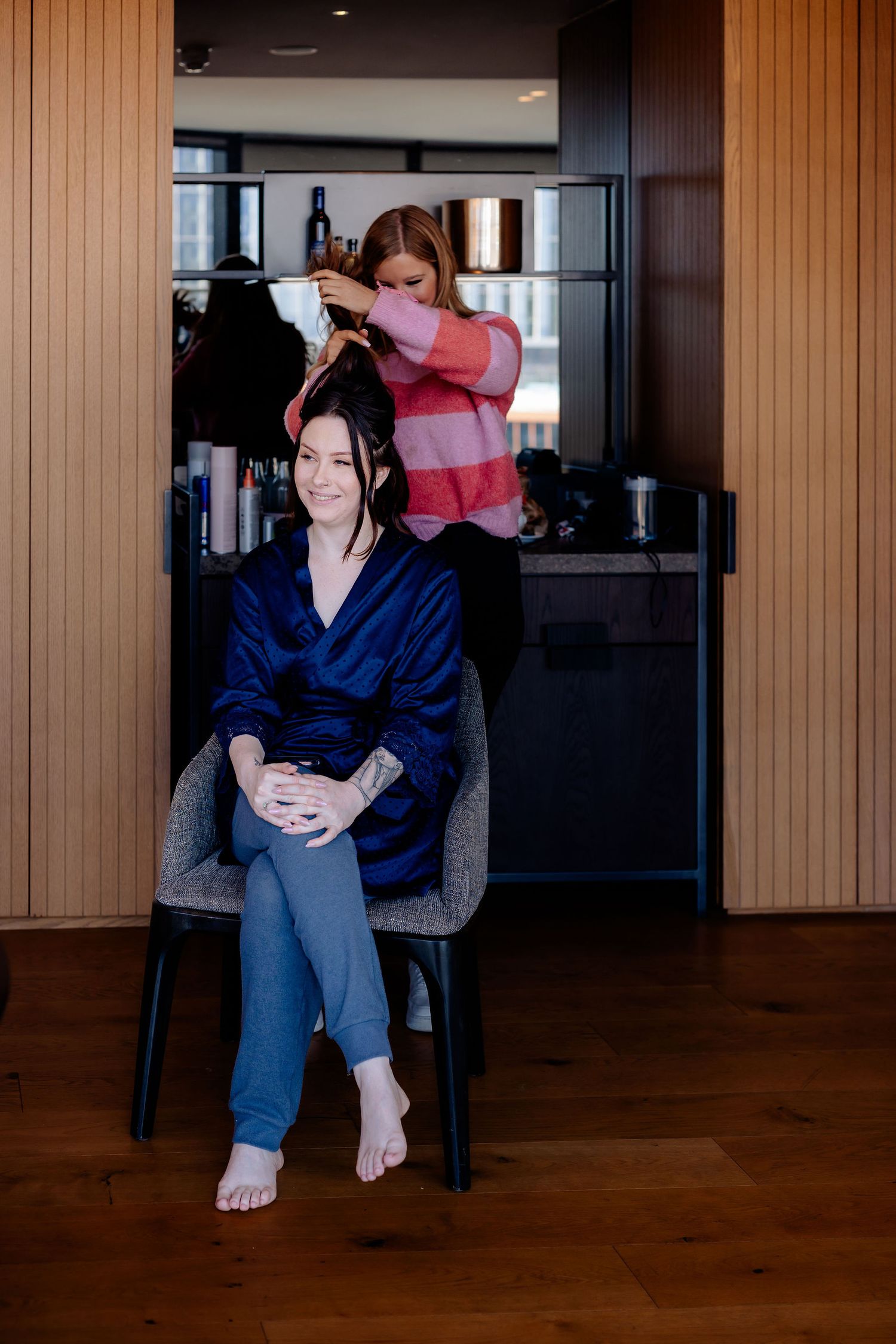 A person in a blue robe getting their hair styled in a modern salon setting.
