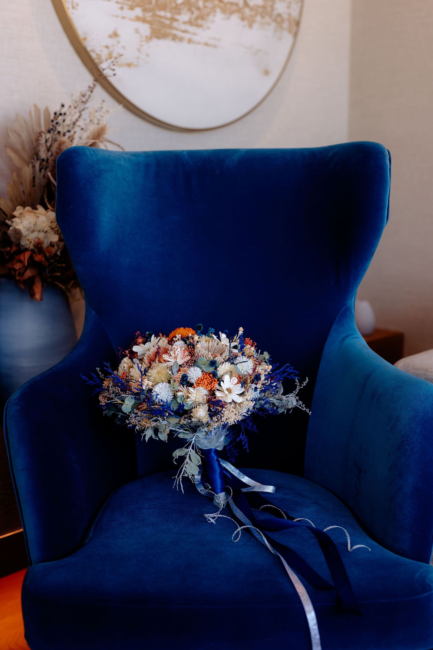 A sequence showing a dark blue velvet sofa adorned with a delicate floral arrangement from different angles.