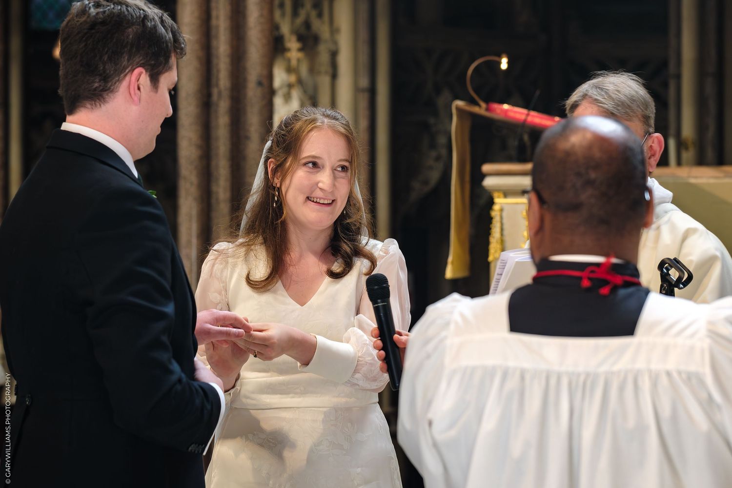 A couple exchanges vows during their traditional church wedding ceremony while a priest looks on.