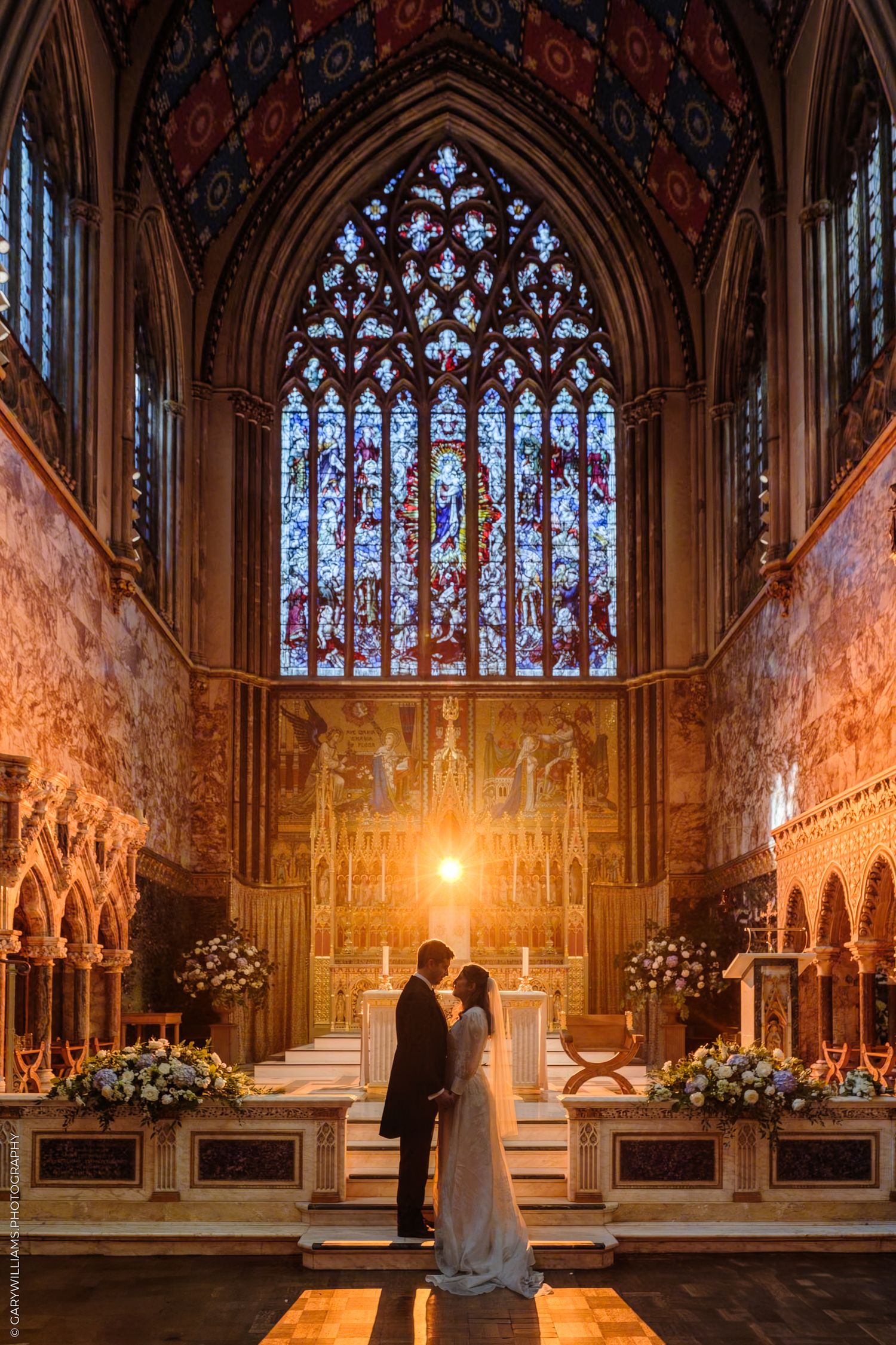 Beautiful Gothic church interior with ornate altar, stained glass windows, and glowing candles illuminating the sanctuary.