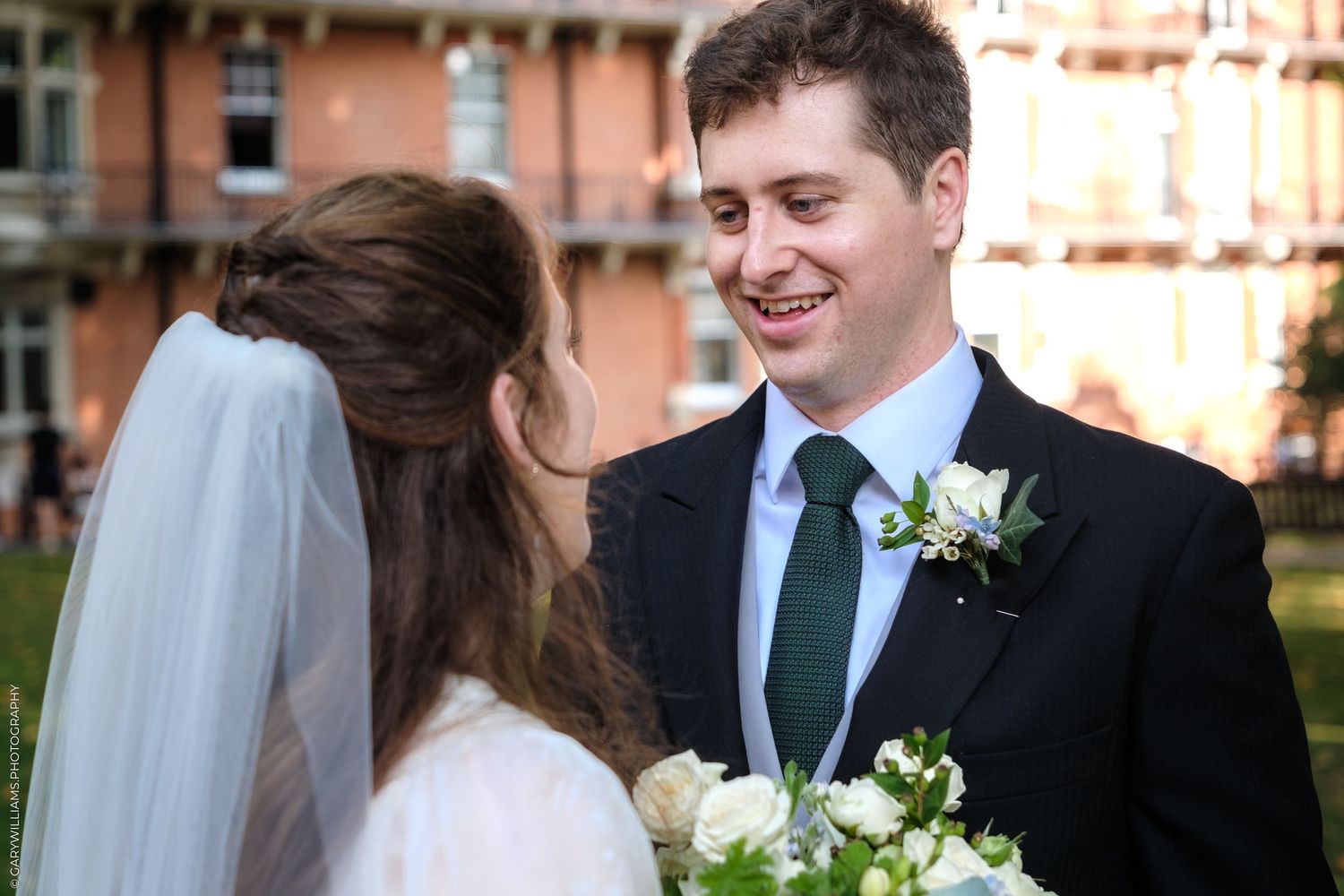 Happy couple share loving glances and smiles during an outdoor wedding ceremony at sunset.