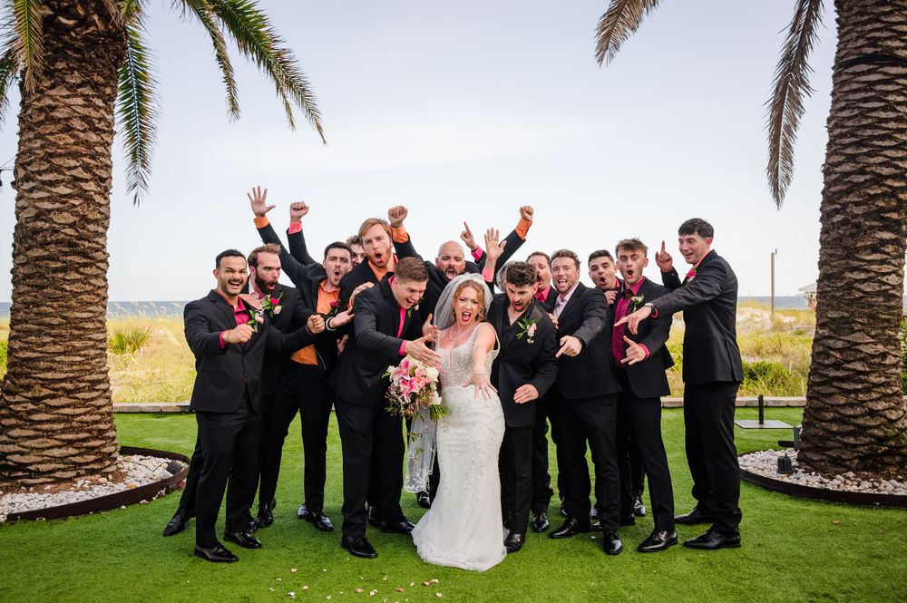Celebratory group photo outdoors between palm trees on a sunny day.