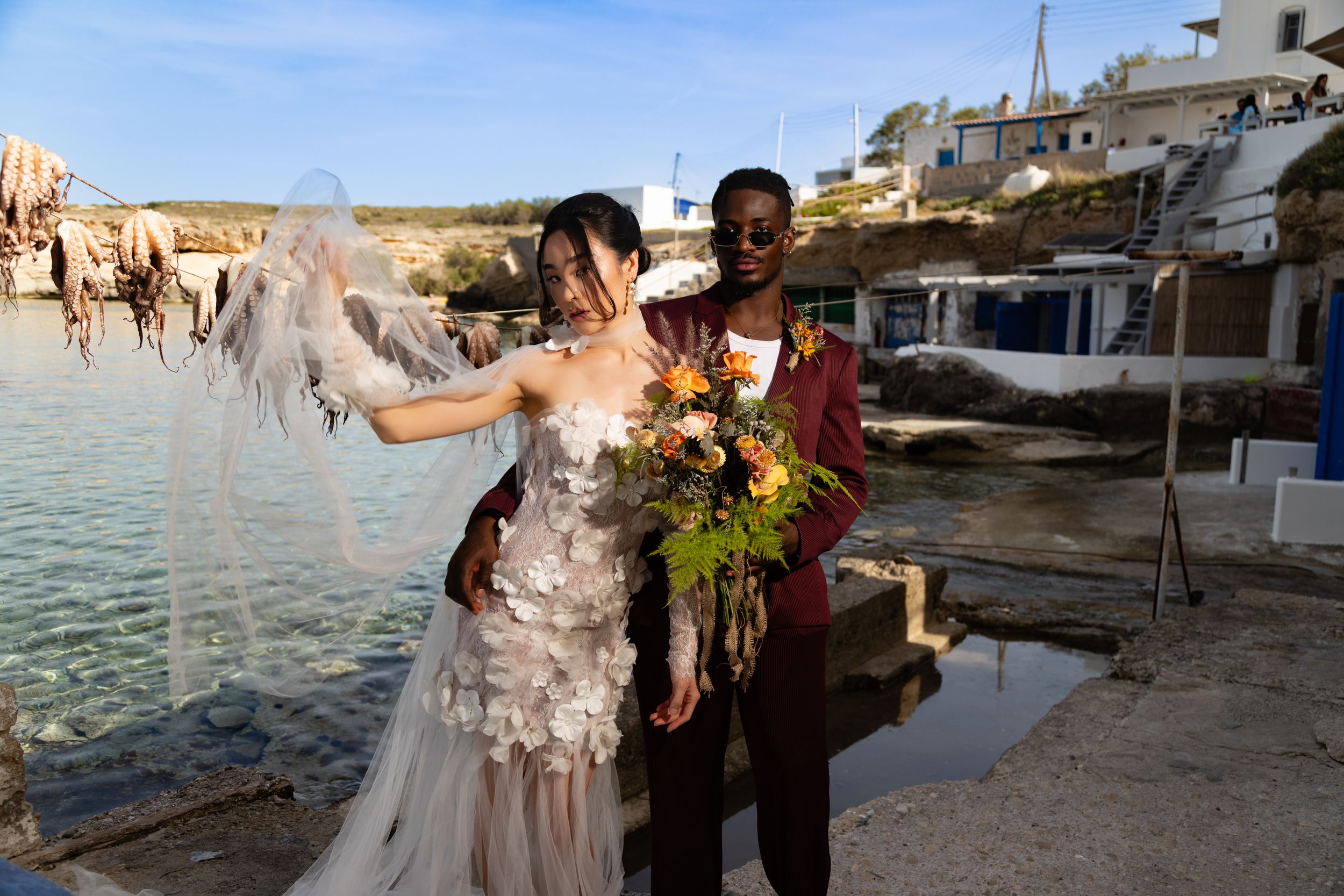 Wedding celebration on a scenic beach with buildings and coastline in the background.